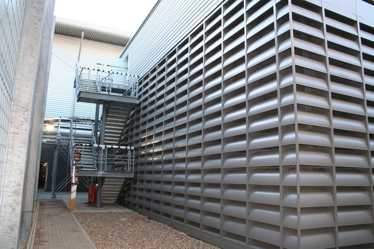 Bâtiment industriel comportant deux façades en grilles acoustiques de ventilation à lames courbées