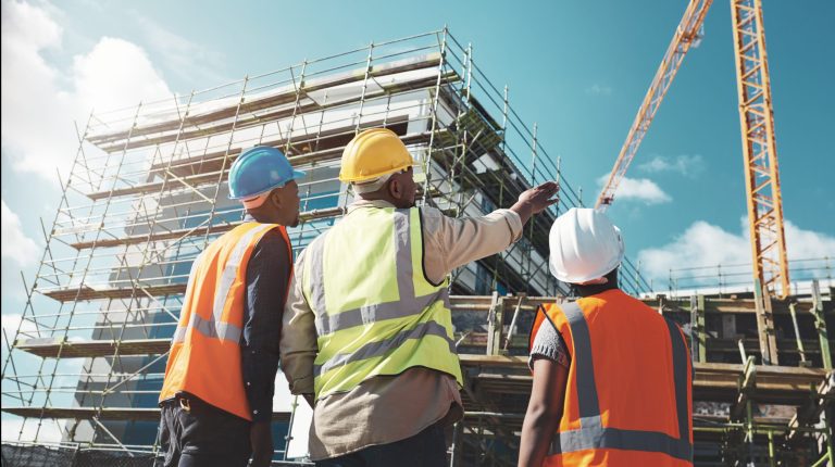 Ingénierie, chantier de construction et équipe en extérieur pour un projet de bâtiment, avec discussion entre une femme noire et des hommes sur la planification, l’architecture et la sécurité en milieu urbain